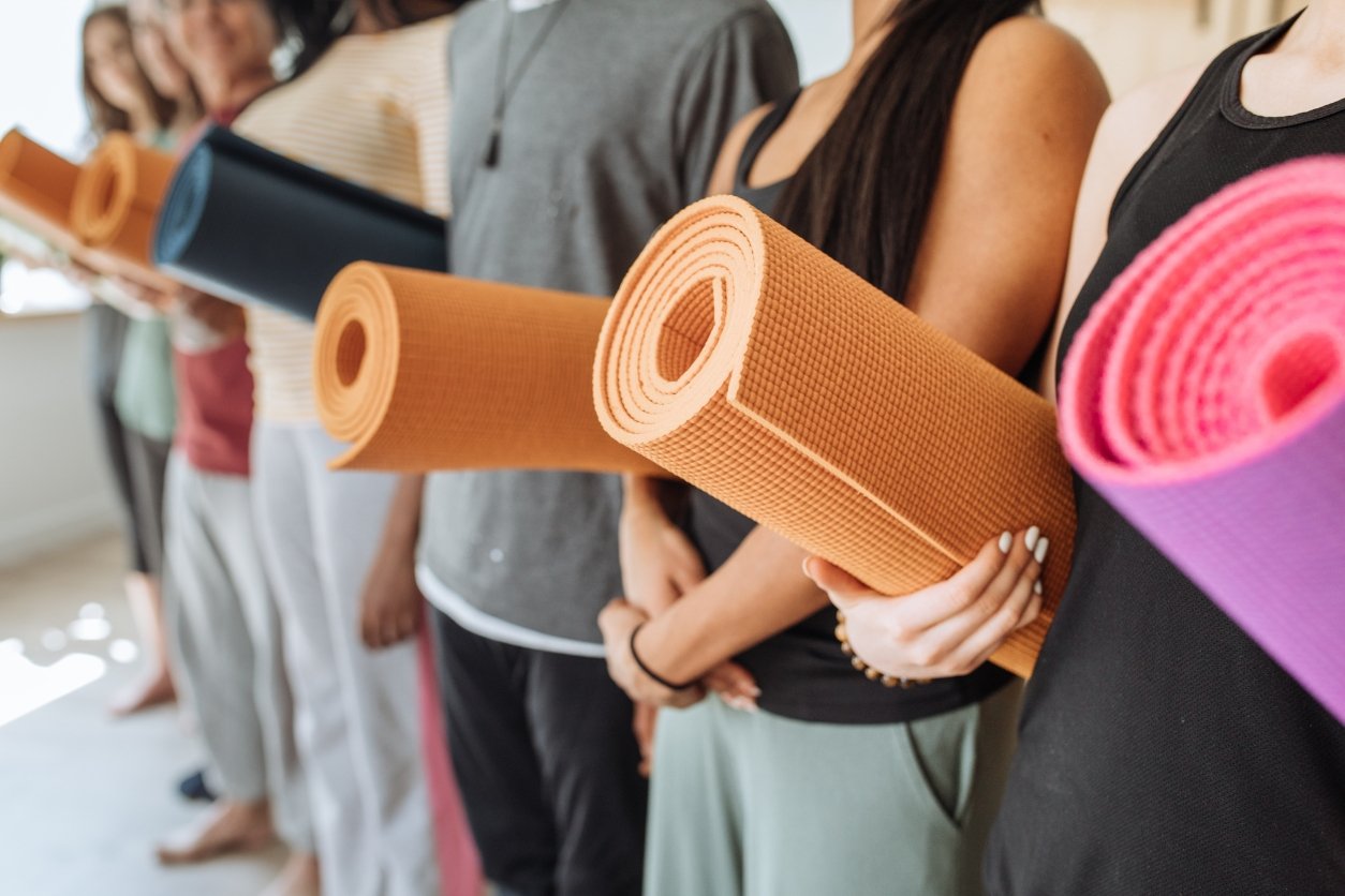 hommes et femmes tiennent le tapis de yoga