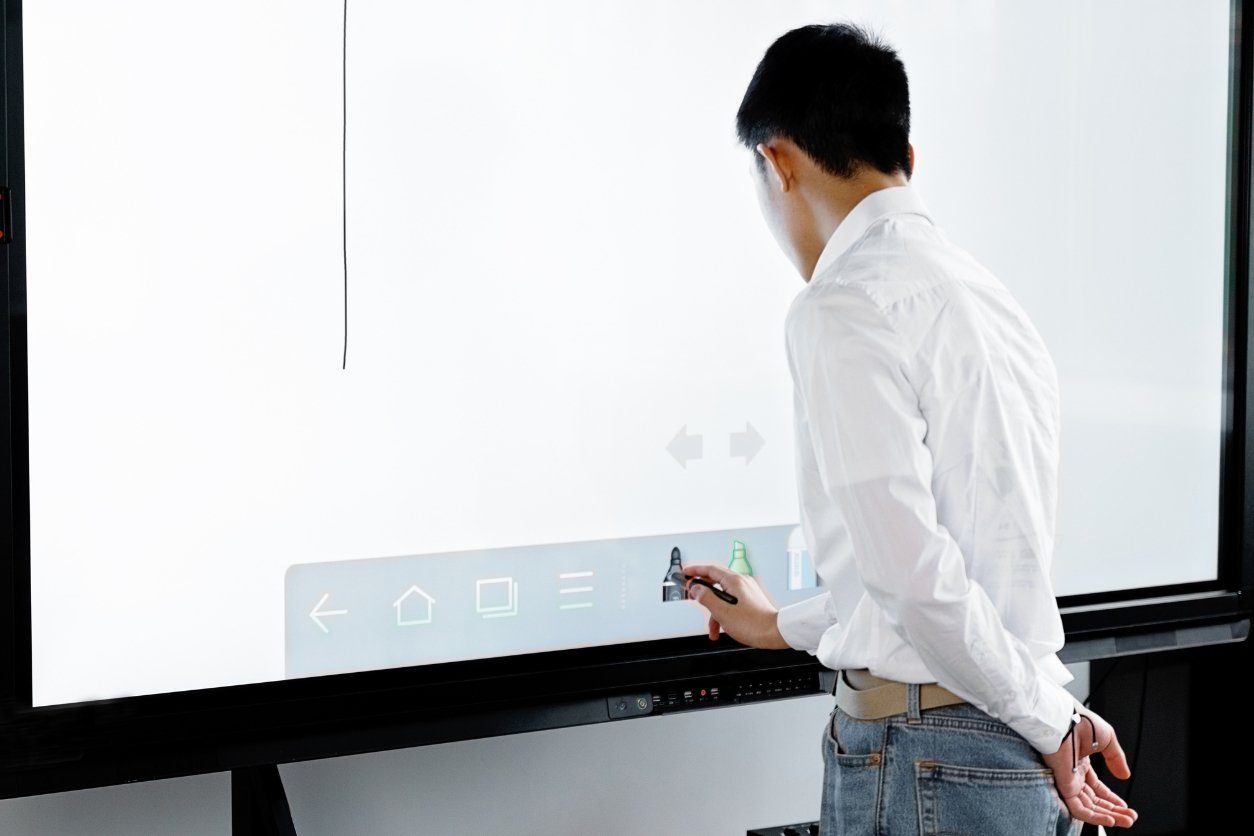 jeune homme entrain d'écrire sur un tableau interactif