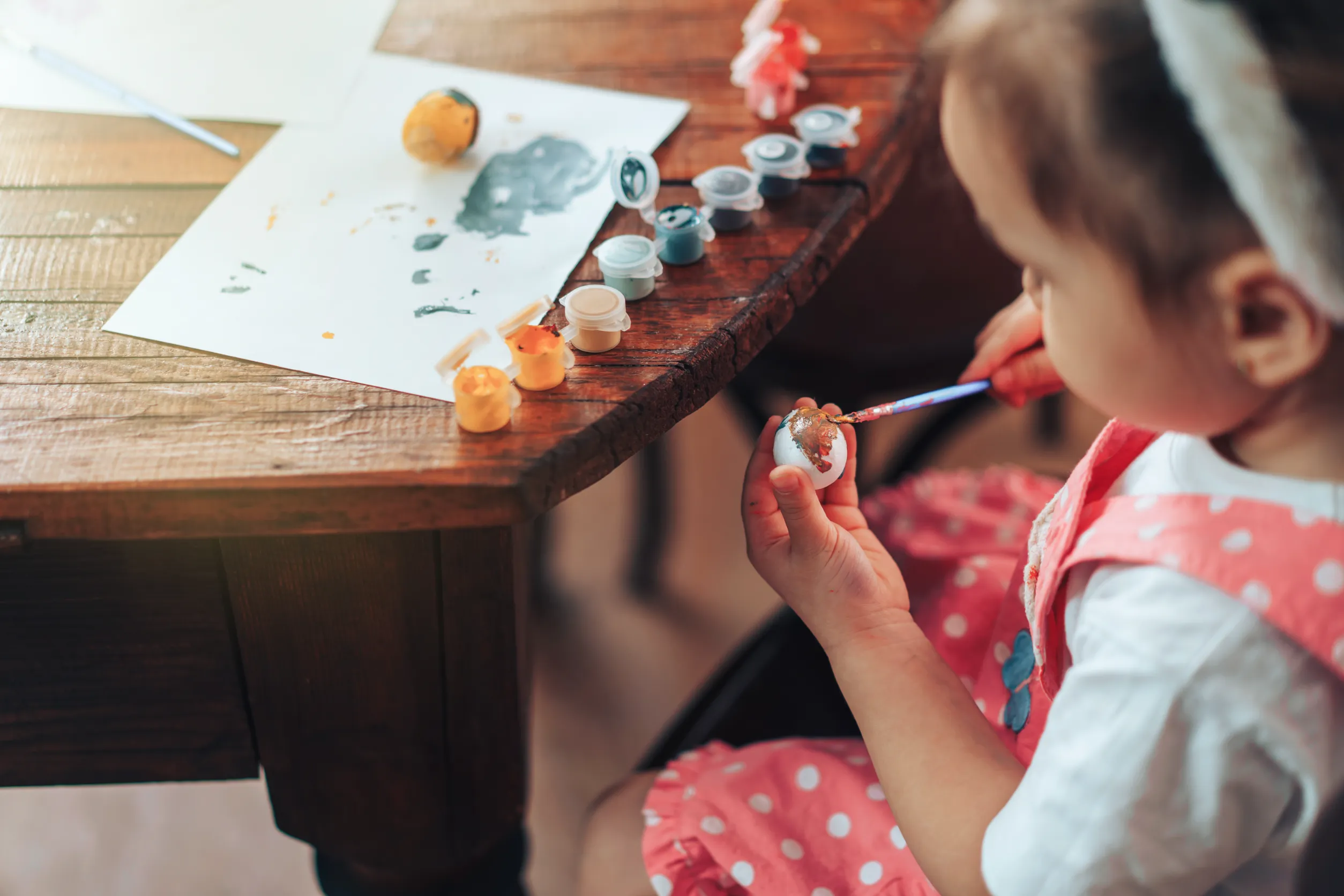 l'enfant peint des œufs sur une table en bois pour les fêtes religieuses