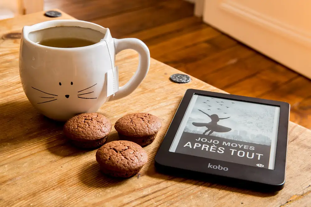 liseuse avec ebook posées à coté de biscuits et café