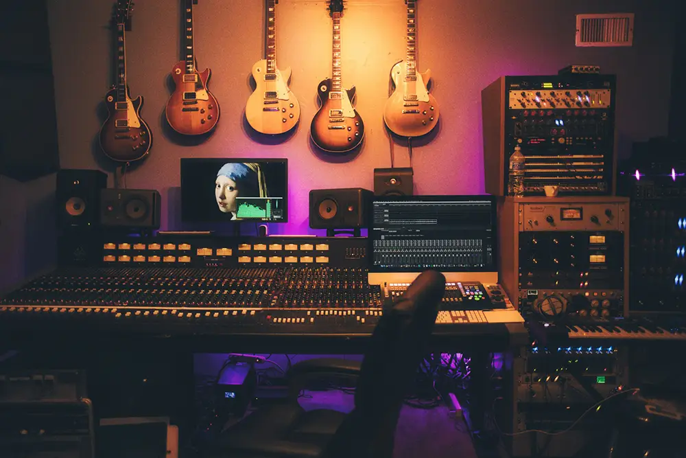 intérieur d'un studio d'enregistrement avec table de mixage, guitares aux murs, et tout l'équipement