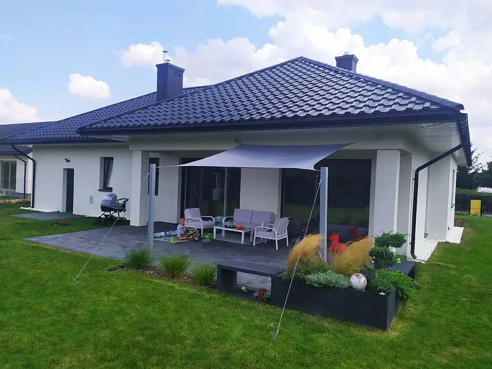 petite maison avec terrasse à l'arrière ombragée par une voile rectangulaire