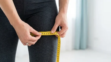 Une personne mesure la taille de sa cuisse pour savoir si elle a maigri des cuisses