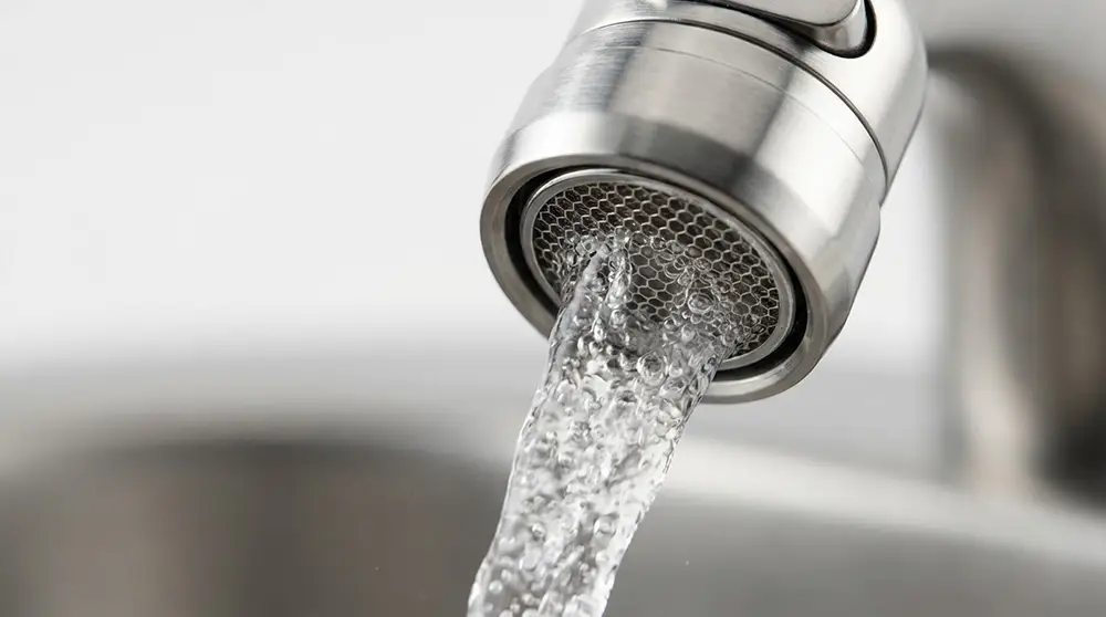 Gros plan sur un mousseur de robinet installé pour réduire la consommation d'eau domicile