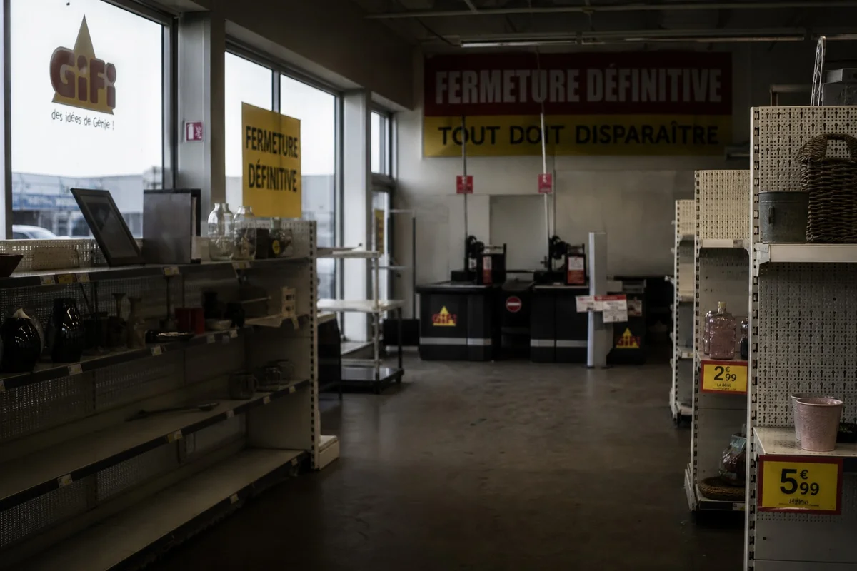 Intérieur désert d'un magasin Gifi avec rayons vides et affiche liquidation en France