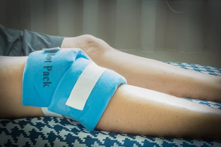 Genou douloureux et inflammé enveloppé d'un hot pack bleu